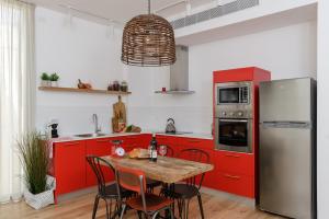 AirTLV - Rambam Residence W Private MAMAD! في تل أبيب: مطبخ مع دواليب حمراء وطاولة مع كراسي
