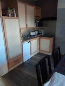 Elle comprend une petite cuisine avec des placards blancs et un réfrigérateur blanc. dans l'établissement Gîte De La Ferme, à Gundolsheim