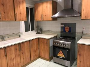 uma cozinha com armários de madeira e um forno com placa de fogão em Ajwaa Suites em Jidá