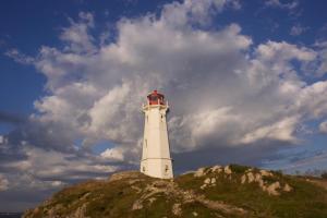 a white lighthouse on top of a hill at Fortress Inn Louisbourg in Louisbourg
