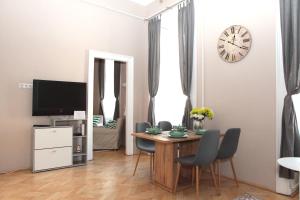 uma sala de jantar com uma mesa e um relógio na parede em Budapest Palace Apartment - Palace District - Downtown em Budapeste