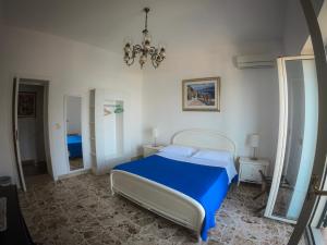 a bedroom with a blue bed and a chandelier at Villa Maremonti in Taormina