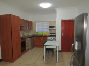a kitchen with wooden cabinets and a table and a refrigerator at Vista Bonita Apartments in Mossel Bay