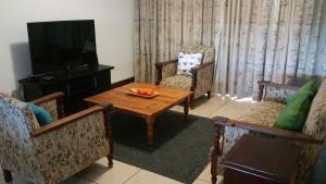 a living room with a table and chairs and a television at Vista Bonita Apartments in Mossel Bay