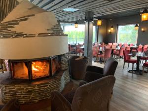 a fireplace in a restaurant with tables and chairs at Hotel Rukatonttu in Ruka