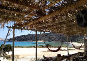 a beach with two hammocks under a straw roof at Kritamos suites in Irakleia