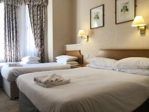 a hotel room with two beds with towels on them at Ullswater Hotel in Bournemouth +46 photos