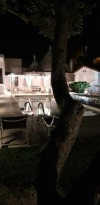 a tree in front of a building with a table at Al Trulletto in Ceglie Messapica