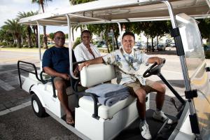 three men are sitting in a golf cart at Eagle Aruba Resort & Casino in Palm-Eagle Beach