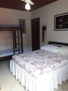 a bedroom with a bed with a floral bedspread at Pousada da Tom-Ubatuba Perequê-Açu in Ubatuba