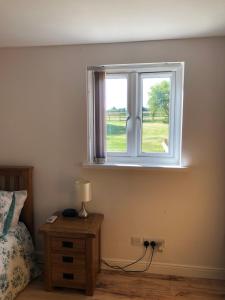 a bedroom with a window and a table with a lamp at The Barn in Wyboston