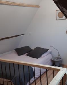 ein Bett mit weißer Bettwäsche und schwarzen Kissen darauf in der Unterkunft Le nid douillet in Offrethun