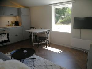 a living room with a table and a kitchen with a window at Hytten Skanör in Skanör med Falsterbo