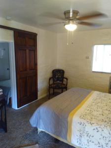 a bedroom with a bed with a ceiling fan and a chair at Grand Canyon West Hotel Sheps Miners Inn in Chloride