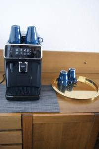 a coffee maker with two mugs on a plate on a table at Ferienwohnung Schwarzwaldlust in Schluchsee