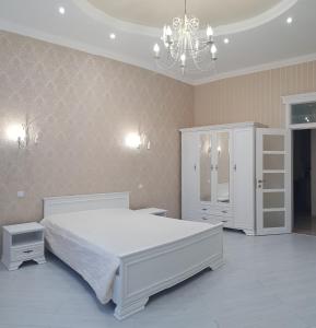 a bedroom with a large white bed and a chandelier at Vip Apartment na Derebasovskoi in Odesa