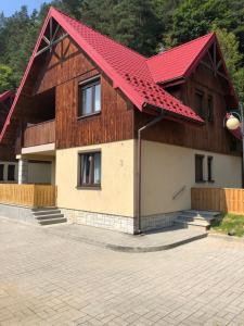 a house with a red roof and a driveway at Domek na Jasnej in Muszyna