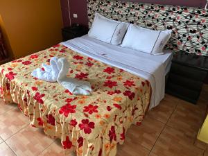 a bedroom with a bed with a floral bedspread and two towels at Manantail Hotel No.003 in Puente Piedra
