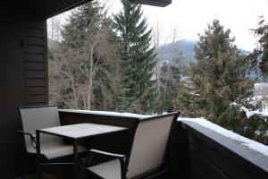 uma mesa e cadeiras numa varanda com vista para as árvores em Rainbow Suites by Whistler Retreats em Whistler