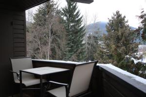einen Tisch und Stühle auf einem Balkon mit Blick auf die Bäume in der Unterkunft Rainbow Suites by Whistler Retreats in Whistler