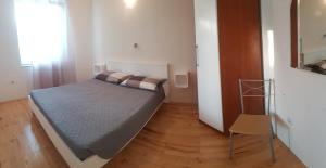 een kleine slaapkamer met een bed en een stoel bij Apartment Anita in Fažana