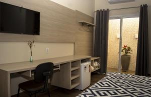 um quarto com uma secretária e uma televisão na parede em Pousada Araxá em Araxá