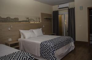 a hotel room with two beds and a window at Pousada Araxá in Araxá