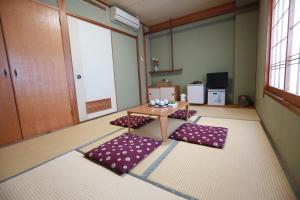 Habitación con mesa y alfombras moradas en el suelo en Hotel Ikeda, en Nagasaki