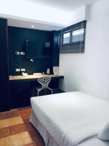 1 dormitorio con 1 cama y escritorio con silla en Lai Chi Te Hotel, en Tainan