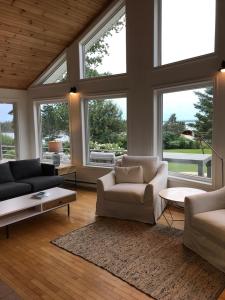 a living room with two couches and a table and windows at Private Waterfront Luxury on the Bras D'Or Lake in Sydney Forks
