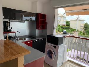 a kitchen with a washing machine and a balcony at Studio ds résidence sécurisée avec vue & accès à la mer . in Le Moule