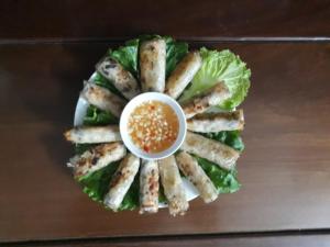 a plate with a sandwich with lettuce and a sauce at Center Tam Coc Homestay in Ninh Binh