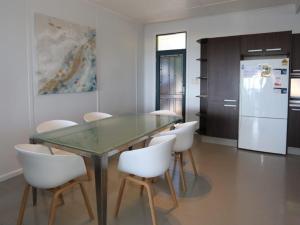 a dining room with a glass table and white chairs at Brilliant Ocean Views in Gerroa