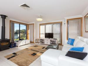 a living room with a white couch and a tv at Coastal Haven at Gerroa in Gerroa