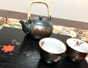 a tea pot and two cups on a table at Osaka Guesthouse SAYURI HONKAN in Osaka