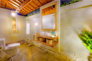 een badkamer met een wit toilet en een wastafel bij Canggu Wooden Green Paradise in Canggu