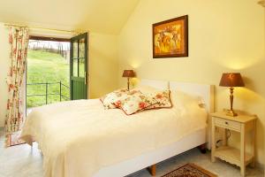 1 dormitorio con 1 cama blanca, ventana y mesita de noche en Vakantie Logies de Kleine Motte, en Sint-Truiden
