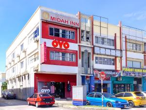 un edificio rosso e bianco con macchine parcheggiate di fronte di Super OYO 502 Midah Inn Puchong a Puchong