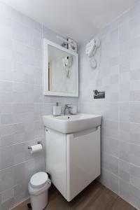 a white bathroom with a sink and a toilet at Mini Hotel Buzzok in Kyiv