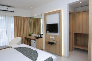 a hotel room with a bed and a flat screen tv at Shikin Hotels (Close to Palm Beach Road) in Navi Mumbai
