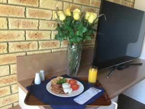 
a table topped with a plate of food and a vase of flowers at Anchor Belle Motel in Warrnambool
