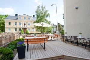 a patio with tables and chairs and an umbrella at Hotell Värend in Växjö