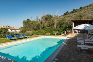 a swimming pool with blue chairs and an umbrella at Agriturismo Monte Cologna in Foligno