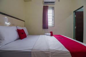 een slaapkamer met een groot wit bed met rode kussens bij RedDoorz near Politeknik Negeri Medan in Medan