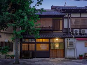 uma casa com uma árvore em frente em Kyoto Machiya Cottage Karigane em Quioto