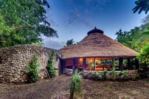 a house with a thatched roof and a building at Lohagarh Corbett Resort in Belparāo