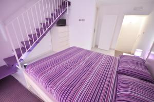 a bedroom with a purple and white bed and stairs at Le sorelle di Napoli in Naples