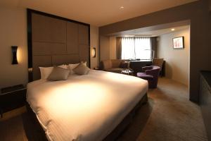 una camera d'albergo con un letto grande e una sedia di Hotel Trusty Nagoya Shirakawa a Nagoya