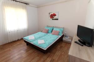 Schlafzimmer mit einem Bett und einem Flachbild-TV in der Unterkunft Apartman Branka in Ližnjan