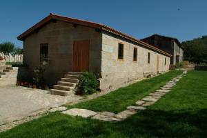 un pequeño edificio de ladrillo con una puerta roja y un poco de hierba en Casa Rural Vilaboa en Allariz